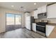 Bright kitchen featuring stainless appliances, white cabinets, slider door access to patio, and gray wood-look floors at 2728 Pavehawk Way, Las Vegas, NV 89156