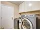 Laundry room featuring modern gray front-load washer and dryer with white cabinets above at 2832 Cape Hope Way, Las Vegas, NV 89121