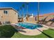 Inviting backyard pool featuring mature palm trees, artificial grass, and ample space for outdoor enjoyment at 326 Fuente Dr, Henderson, NV 89014