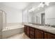 Bathroom with a granite countertop, double sinks, soaking tub, and a separate shower with glass block window at 5067 Pensier St, Las Vegas, NV 89135