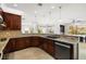 Gourmet kitchen with dark wood cabinetry, granite countertops, stainless steel appliances, and an open layout at 5067 Pensier St, Las Vegas, NV 89135