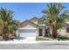 Inviting single-story home featuring desert landscaping with mature palm trees and an attached two-car garage at 5213 Giallo Vista Ct, North Las Vegas, NV 89031