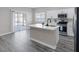 Modern kitchen featuring gray vinyl flooring, white cabinets, stainless steel appliances, and center island at 5213 Giallo Vista Ct, North Las Vegas, NV 89031