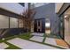 Modern home's striking front entrance featuring sleek, dark doors and minimalist landscaping with lush artificial turf at 609 Sleeping Dragon Dr, Henderson, NV 89012