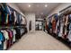 Spacious walk-in closet with custom shelving and ample storage, featuring a full-length mirror and neutral carpeting at 609 Sleeping Dragon Dr, Henderson, NV 89012