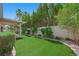 Expansive backyard with artificial turf, mature landscaping, and a covered patio at 8541 Highland View Ave, Las Vegas, NV 89145
