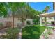 Landscaped backyard featuring artificial turf, mature trees, and a covered patio at 8541 Highland View Ave, Las Vegas, NV 89145