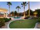 Expansive backyard with a putting green, pool, manicured landscaping, and mature palm trees for outdoor enjoyment at 10243 Cowboys Dream St, Las Vegas, NV 89131