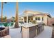 Outdoor kitchen area and beautiful backyard featuring a pool, covered patio, built-in grill, and a cozy fire pit at 10243 Cowboys Dream St, Las Vegas, NV 89131