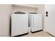 A laundry room with tile floors, a shelf, a trash can, and a front-loading washer and dryer at 10243 Cowboys Dream St, Las Vegas, NV 89131