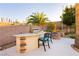 Outdoor bar area with seating and BBQ grill adjacent to fire pit and backyard trees at 10243 Cowboys Dream St, Las Vegas, NV 89131