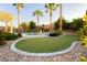 Manicured backyard putting green with mature palm trees, water feature and bench at 10243 Cowboys Dream St, Las Vegas, NV 89131