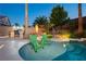 Inviting swimming pool with inset chairs, a stone surround, and mature tropical landscaping creating a backyard paradise at 10243 Cowboys Dream St, Las Vegas, NV 89131