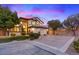 Elegant two-story home with a well-manicured lawn and spacious driveway at dusk at 10668 Porta Romana Ct, Las Vegas, NV 89141