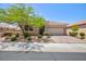 Well-manicured single story home with desert landscaping, trees, and a paved driveway leading to a two-car garage at 1081 Via Gandalfi, Henderson, NV 89011