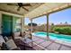Relaxing covered patio featuring comfortable seating, a ceiling fan, and views of the pool and landscaped backyard at 1081 Via Gandalfi, Henderson, NV 89011