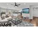 Bright, staged living room with hardwood floors, ceiling fan, modern kitchen, dining area, and an entertainment center at 1109 Maserati Dr, Las Vegas, NV 89117