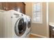 Laundry room with front-loading machines and wooden cabinets at 11228 Hedgemont Ave, Las Vegas, NV 89138