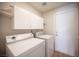 Well lit laundry room with white washer, dryer, cabinets and shelves at 1620 Western Lily St, Las Vegas, NV 89128