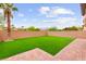 An enclosed backyard with lush artificial grass, palm tree and desert landscaping at 1887 Hollywell St, Las Vegas, NV 89135