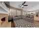 Inviting living room features a cozy fireplace, ceiling fan, and gray sectional with view to the kitchen at 2113 Waterbury Ln, Las Vegas, NV 89134