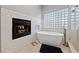 Modern main bathroom featuring a fireplace and a soaking tub next to a glass block window at 2113 Waterbury Ln, Las Vegas, NV 89134