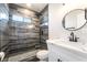 A modern bathroom features marble wall tile, a glass enclosed shower, and a round mirror at 266 Tungsten St, Henderson, NV 89015