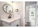 Modern bathroom features a white vanity with a round mirror and black hardware at 266 Tungsten St, Henderson, NV 89015