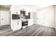 Kitchen with white cabinets, stainless steel appliances, dark backsplash, and gray hardwood flooring at 266 Tungsten St, Henderson, NV 89015