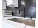 Close-up of the kitchen featuring stainless steel sink, faucet, and a sleek black tile backsplash at 266 Tungsten St, Henderson, NV 89015