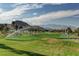 Beautiful golf course featuring lush green grass, trees, and distant mountain views under a partly cloudy sky at 281 Powerbilt Ave, Las Vegas, NV 89148