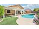 Inviting backyard oasis featuring a sparkling pool, spa, covered patio, and lush artificial grass at 3913 Ricebird Way, North Las Vegas, NV 89084