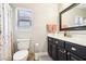 Well-lit bathroom featuring a toilet, vanity with a dark cabinet, and a shower with a floral curtain at 3913 Ricebird Way, North Las Vegas, NV 89084
