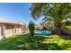 A private backyard with a fenced in pool, shade trees, and grassy area at 4735 Roby Grey Way, North Las Vegas, NV 89081