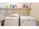Functional laundry room featuring a white washer and dryer with shelving stocked with laundry supplies at 5852 Clear Haven Ln, North Las Vegas, NV 89081