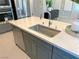 Close-up of a kitchen island featuring a stainless steel sink, quartz countertop, and gray cabinetry, perfect for meal prep at 6511 Dove Point Pl, Las Vegas, NV 89130