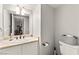 A half bathroom with a single sink, toilet, decorative mirror and neutral color palette at 6624 Jade Jaguar St, North Las Vegas, NV 89086