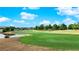View of a well-manicured green on the golf course with mature trees and a pond at 6940 Emerald Springs Ln, Las Vegas, NV 89113
