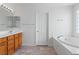 Bright bathroom featuring a tiled floor, a bathtub, and a wood vanity at 7756 River Mist Ct, Las Vegas, NV 89113