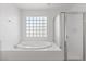 Bathroom features a glass block window, a shower, and a bathtub with white tile at 7756 River Mist Ct, Las Vegas, NV 89113
