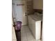 Well-lit laundry room with white appliances, white tiled floor and white door to outside at 7894 W Patrick Ln, Las Vegas, NV 89113