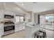 Bright kitchen featuring stainless steel appliances, island with breakfast bar, tile flooring, and sliding doors to backyard at 832 Seco Verde Ave, Henderson, NV 89015