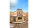 Stone outdoor fireplace with space for grilling and entertaining in a cozy backyard setting at 8337 Willow Basin Ct, Las Vegas, NV 89131