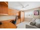 Well-lit office with built-in wooden cabinetry, a ceiling fan, and a comfortable seating area by the window at 9404 Low Tide Ct, Las Vegas, NV 89117