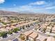 High-angle view of a residential area with similar houses, manicured streets, and mountains in the background on a sunny day at 9541 Vast Valley Ave, Las Vegas, NV 89148