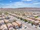 A high-angle shot exhibits a planned community, showcasing uniform homes and a backdrop of rugged mountains and a clear sky at 9541 Vast Valley Ave, Las Vegas, NV 89148