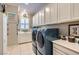 Spacious laundry room with abundant white cabinetry, a sink, and modern blue washer and dryer units at , Henderson, NV 89011