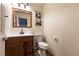 A cozy half-bathroom features a wood vanity, white countertop, matching mirror, and comfort height toilet at , Las Vegas, NV 89131
