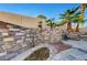 Charming backyard featuring a stone waterfall feature, lush palm trees, and a relaxing lounge area at 1060 Neil Armstrong Cir, Las Vegas, NV 89145
