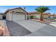 Spacious driveway leading to a two-car garage, complemented by desert landscaping and mature palm trees at 1060 Neil Armstrong Cir, Las Vegas, NV 89145